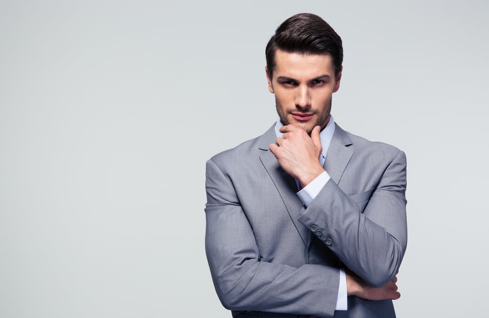 Portrait of a pensive businessman touching his chin over gray background